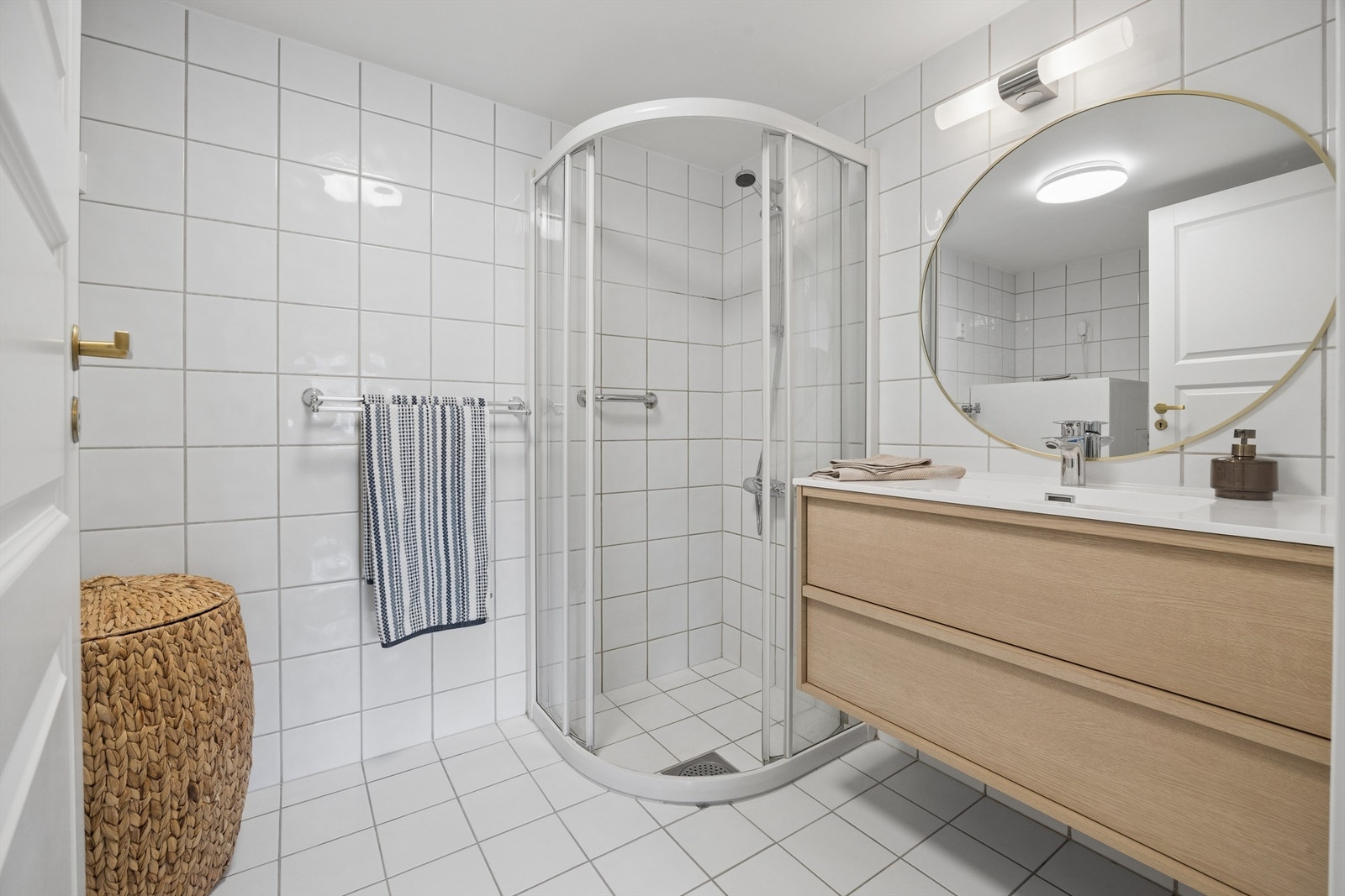 Badet har flislagte overflater, gulvvarme og et praktisk dusjhjørne med skyvedørsramme. Galleribilde