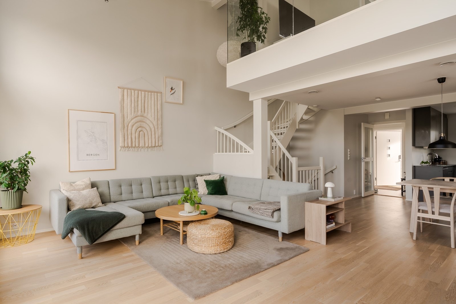 Den åpne trappen og hems-/loftsløsningen over deler av rommet gir en spennende arkitektonisk kvalitet, samtidig som glassveggen på loftet bidrar til å bevare lys og åpenhet mellom etasjene. Galleribilde
