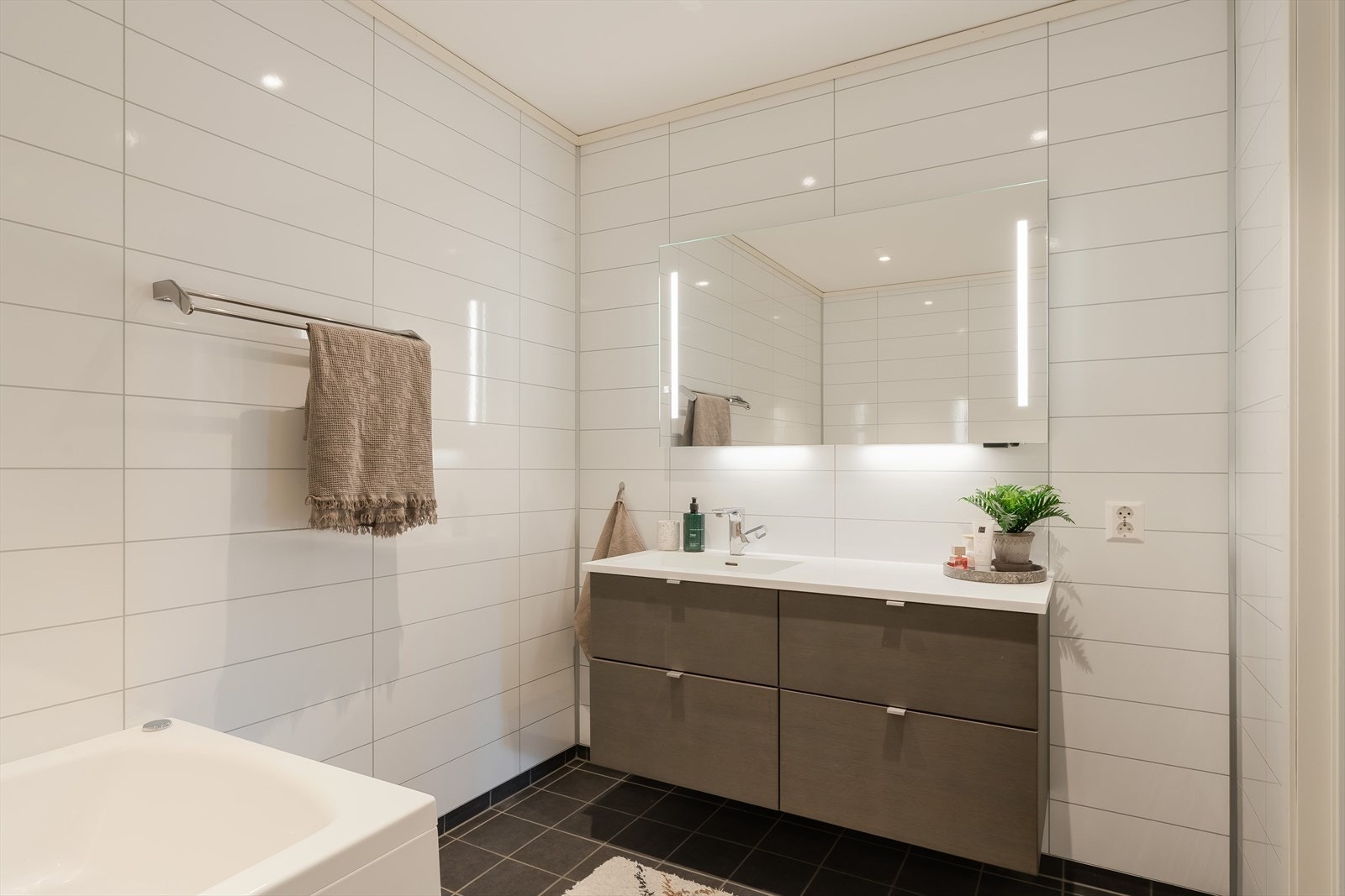 Den brede servantinnredningen med speil og integrert belysning gir både godt med oppbevaring og en ryddig hverdagsfunksjon. I tillegg til badet har boligen et eget vaskerom. Galleribilde