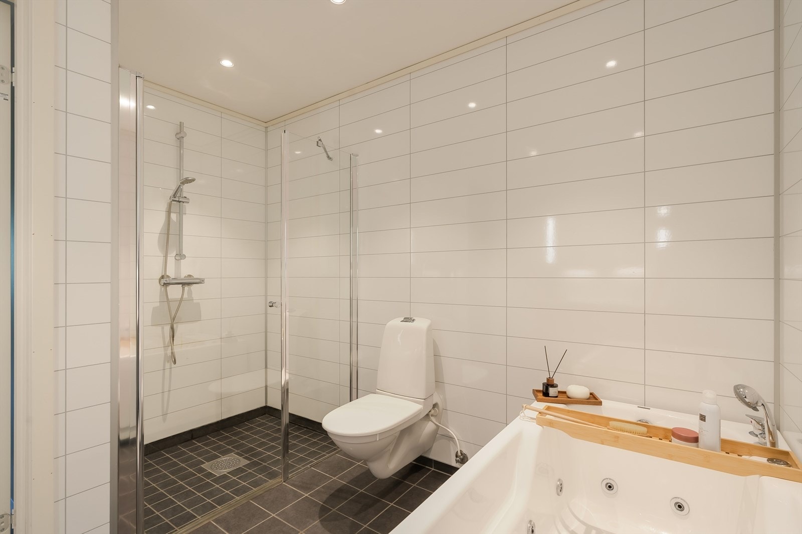 Badet i sokkeletasjen er romslig og moderne, med en stilren kombinasjon av lyse baderomspanel og mørkere gulvfliser. Galleribilde
