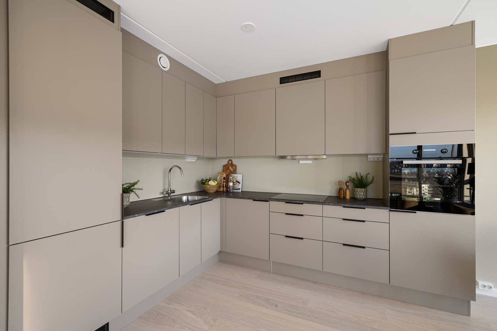 Stilrent kjøkken med integrerte hvitevarer fra Miele, stekeovn i høyskap og ventilator fra RørosHetta (obs: foto er av speilvendt naboenhet - avvik kan forekomme). Galleribilde