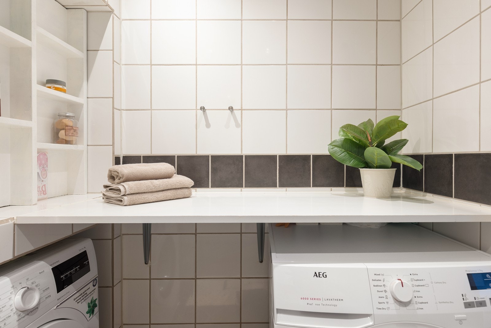 Praktisk opplegg for vaskemaskin. Baderomsinnredning, speil og vegghengt toalett er fra 2023. Galleribilde