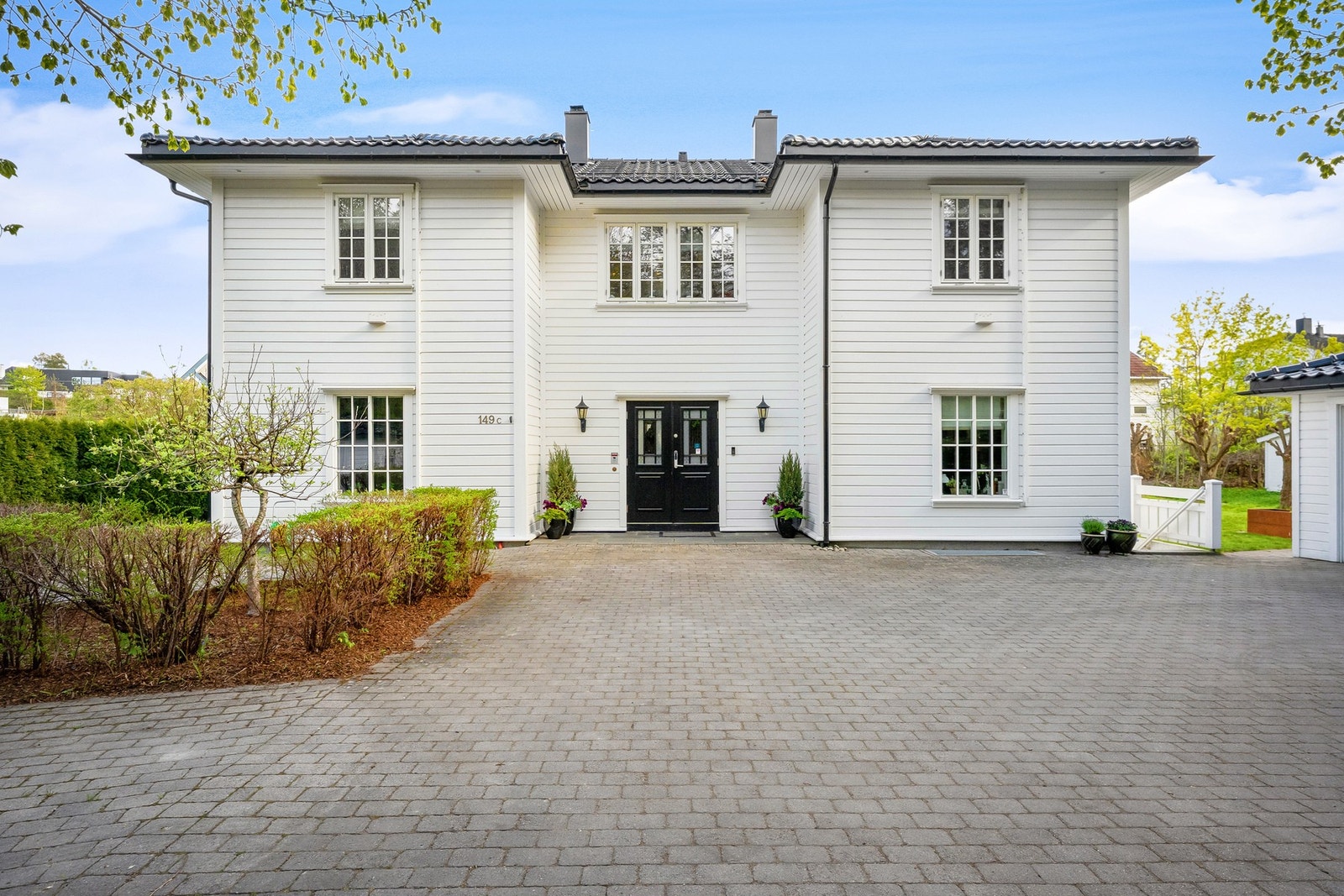 Stor gårdsplass belagt med belegningsstein gir et ryddig og representativt ankomstparti. Galleribilde