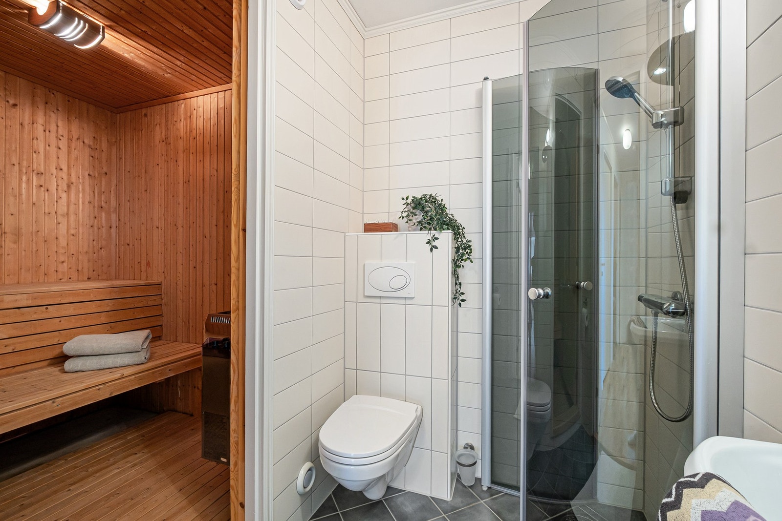 Dette badet har veggmontert toalett, dusjhjørne og direkte tilgang til badstue. Galleribilde