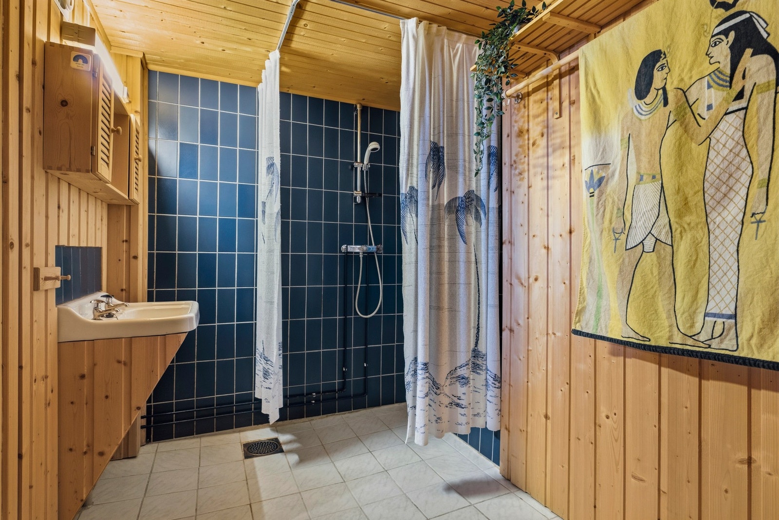 Badet i kjelleren har flislagt gulv og vegger i dusjsonen og servant Galleribilde