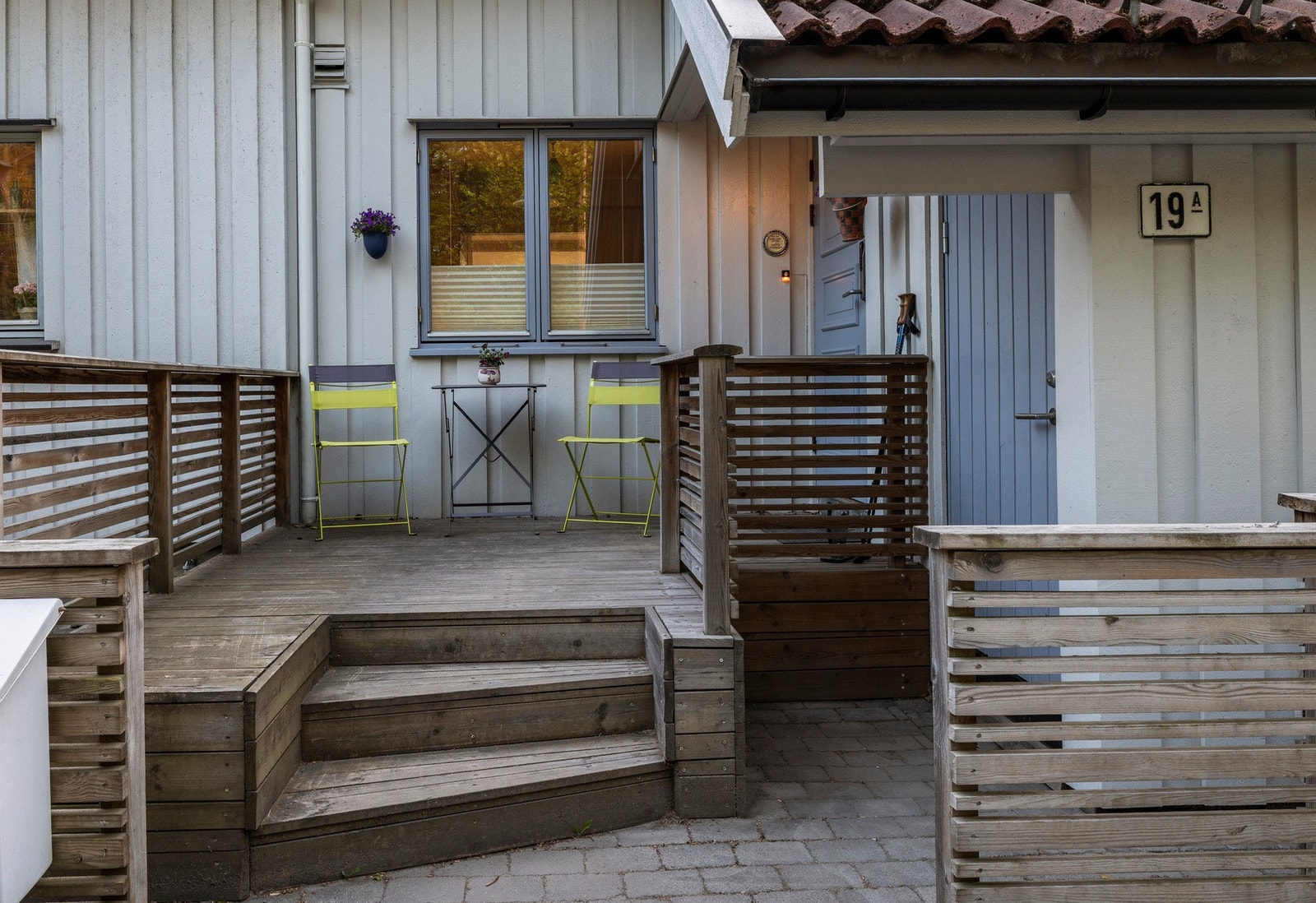Inngangsparti med treterrasse og rekkverk, samt trappetrinn opp til inngangsdør Galleribilde