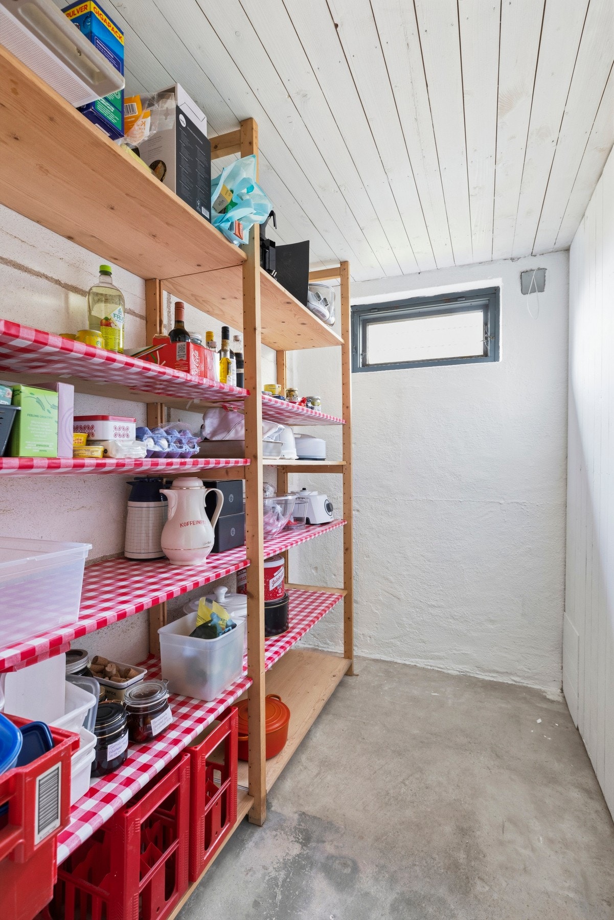 Lyst rom med hyller og et lite vindu som slipper inn naturlig lys Galleribilde