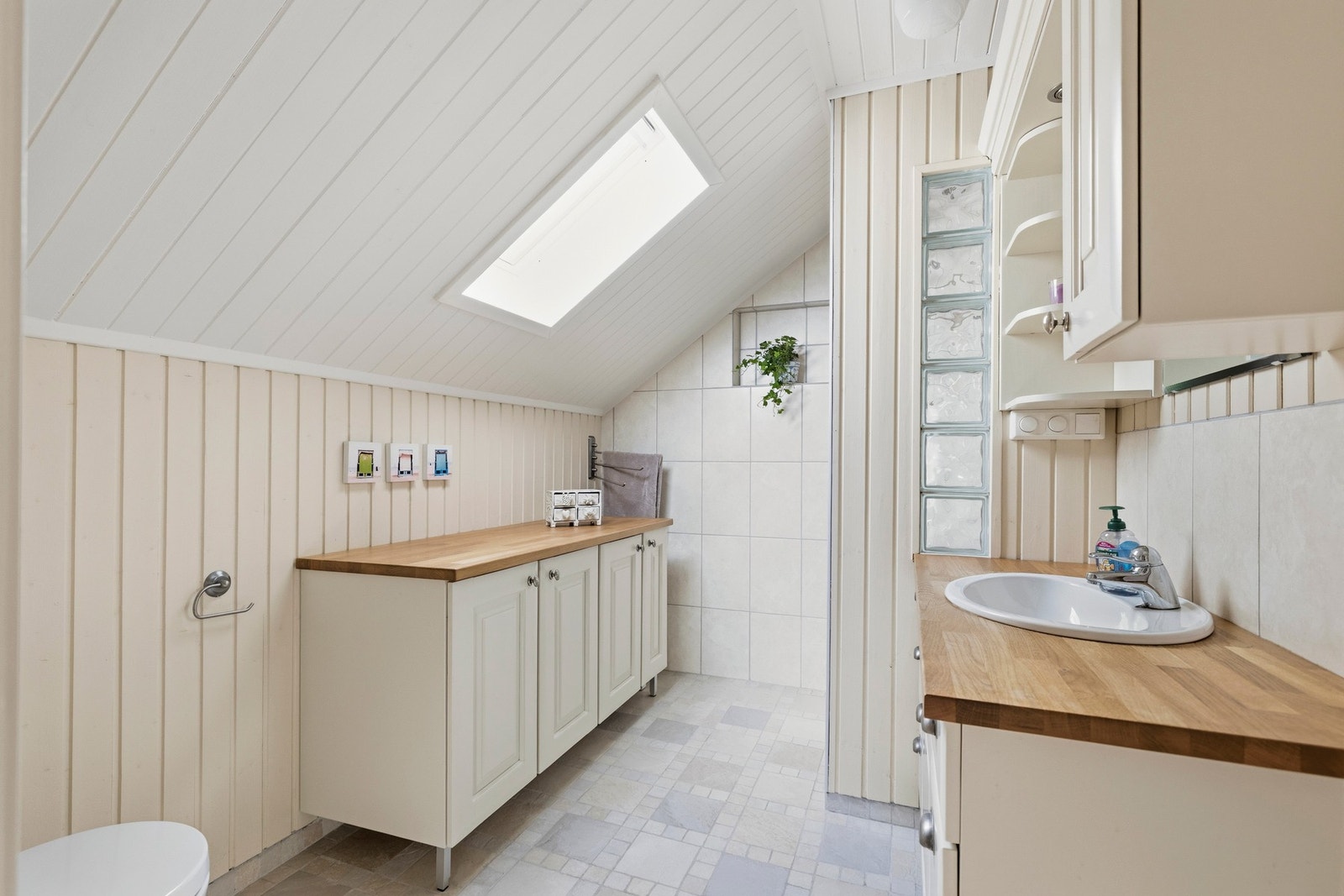 Badet har flislagte gulv og vegger i dusjsonen, mens øvrige vegger er kledd med panel Galleribilde