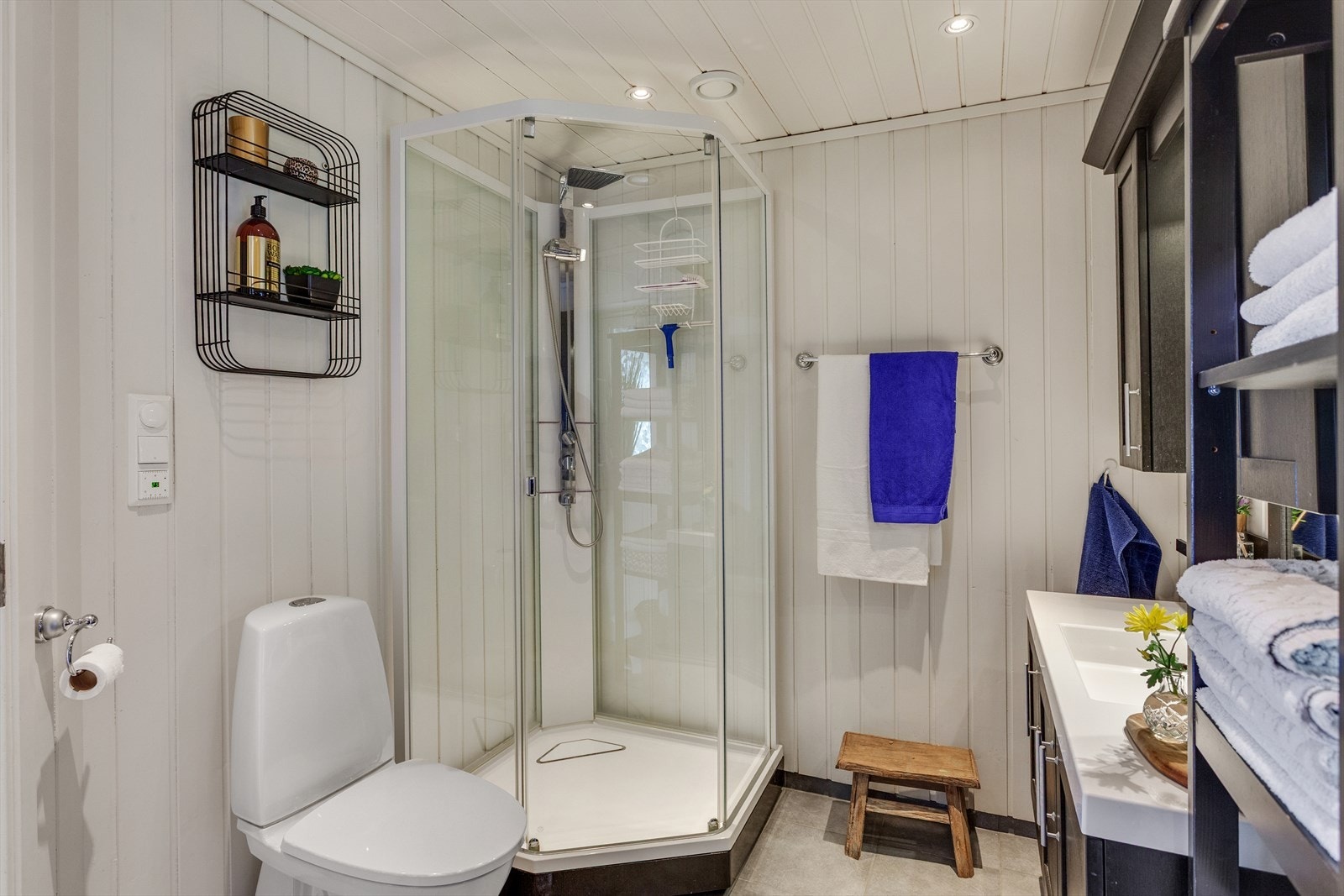 Badet har flislagt gulv, trepanel på veggene, dusjkabinett og servantinnredning. Galleribilde