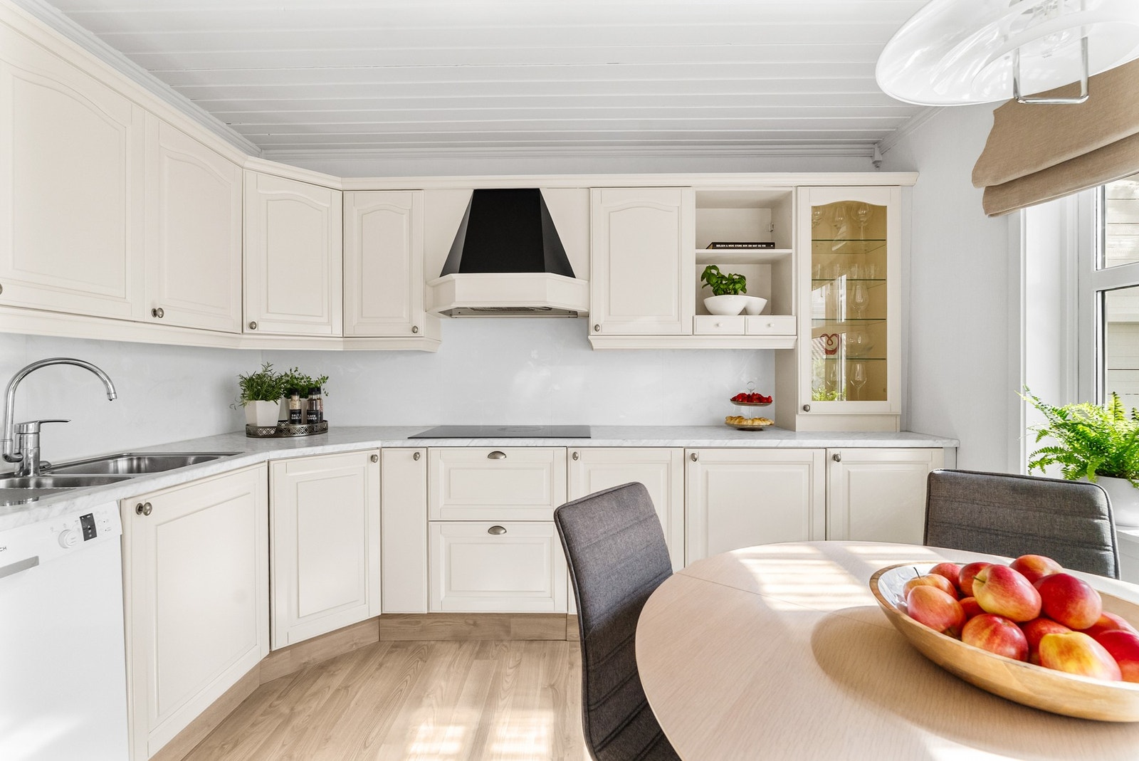 Benkeplaten i laminat har underlimt vask, og veggen over benken er kledd med kitchenboardplater. Galleribilde