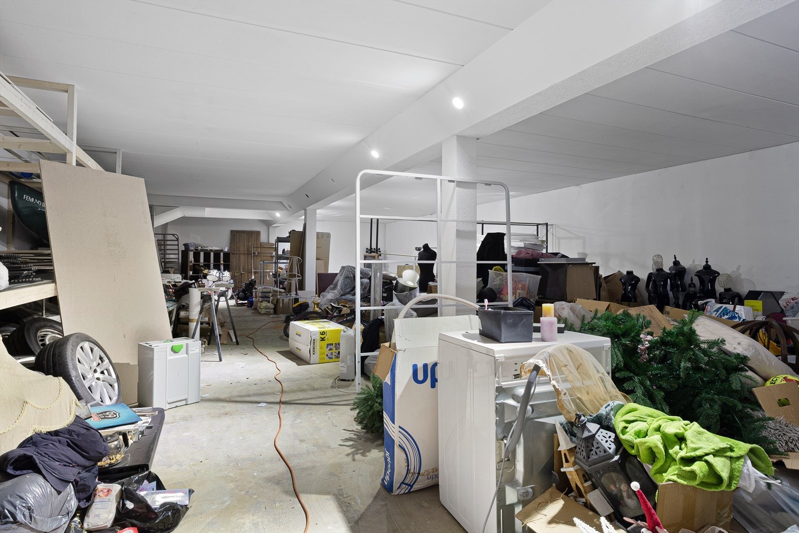 Kjelleren består av store lagerarealer med støpt gulv. I seksjoneringen og rammetillatelsen er arealet godkjent og planlagt som garasje, med totalt fire parkeringsplasser etablert som tilleggsareal til seksjon 1 og 2. Galleribilde