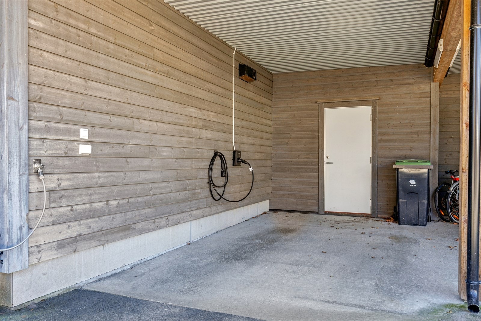 Det er en carport med mulighet for oppbevaring og lademulighet for elbil Galleribilde