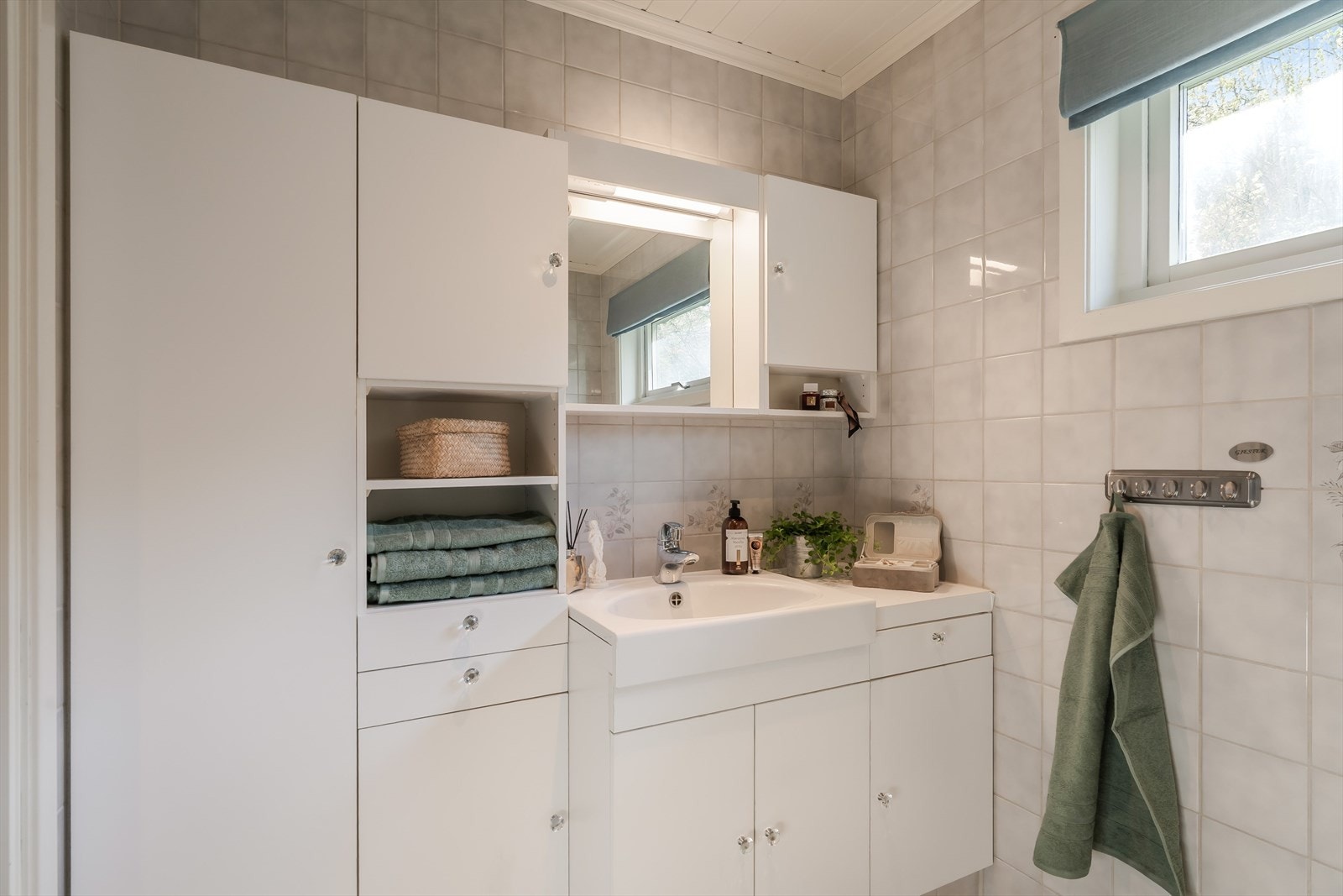 Badet i hovedetasjen er flislagt på gulv og vegger, og har en praktisk innredning med servant, speil med belysning, skapplass, toalett og dusjhjørne med buede glassdører. Galleribilde
