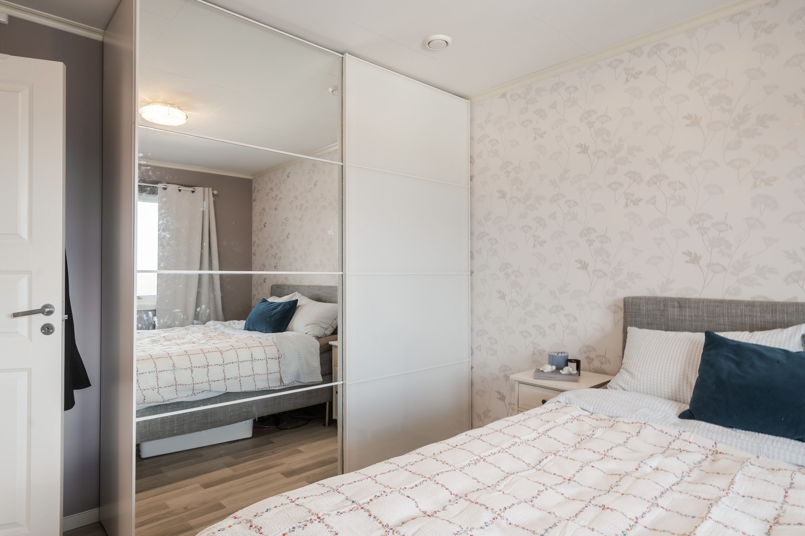 Overflatene er holdt i rolige fargetoner, med en lys tapetsert fondvegg og mørkere kontrastvegg som gir rommet en lun og avdempet atmosfære. Galleribilde