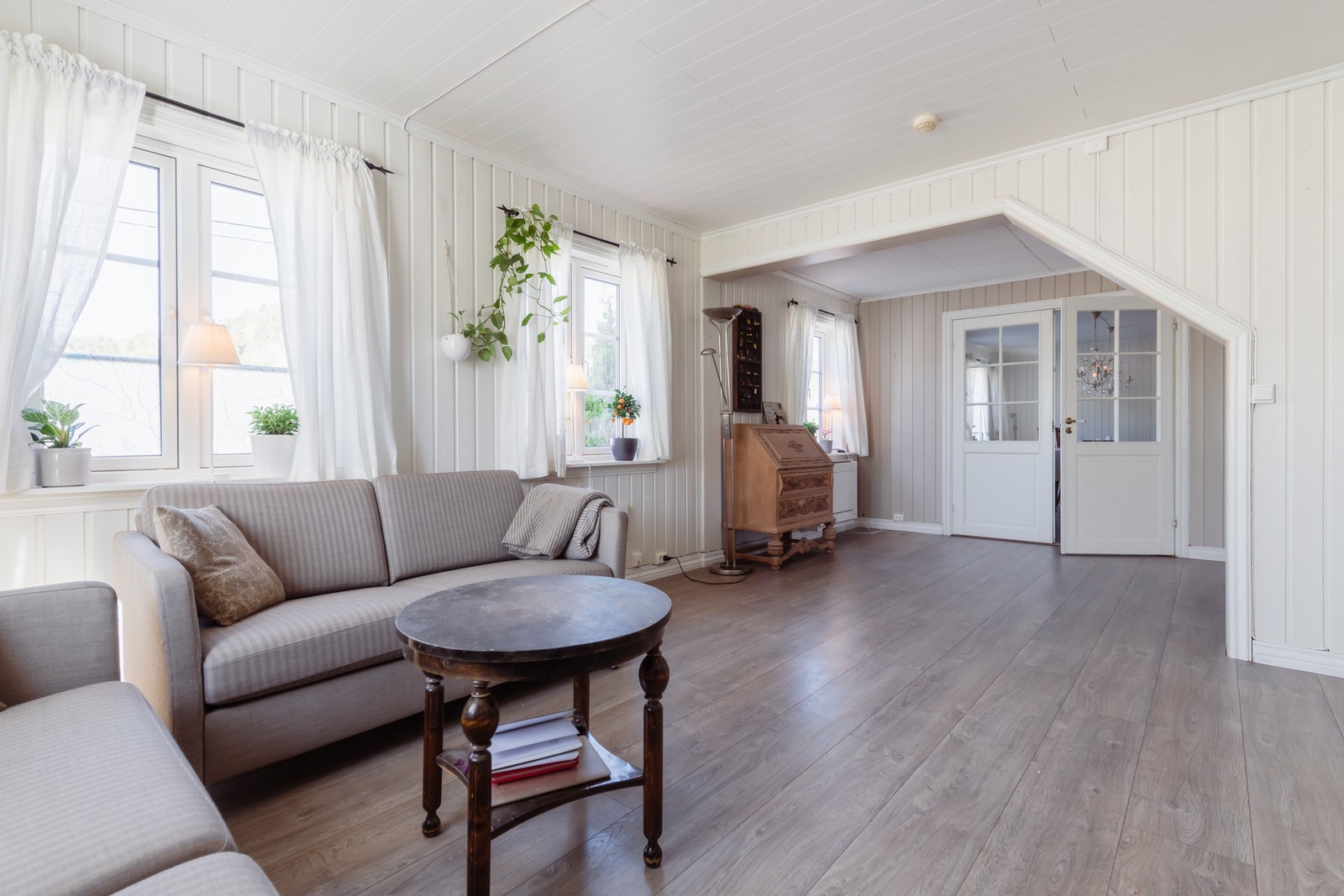 Stuene skilles av en dobbel glassdør, og er begge innredet med 1-stavs laminatgulv og hvitmalte panelvegger. Galleribilde