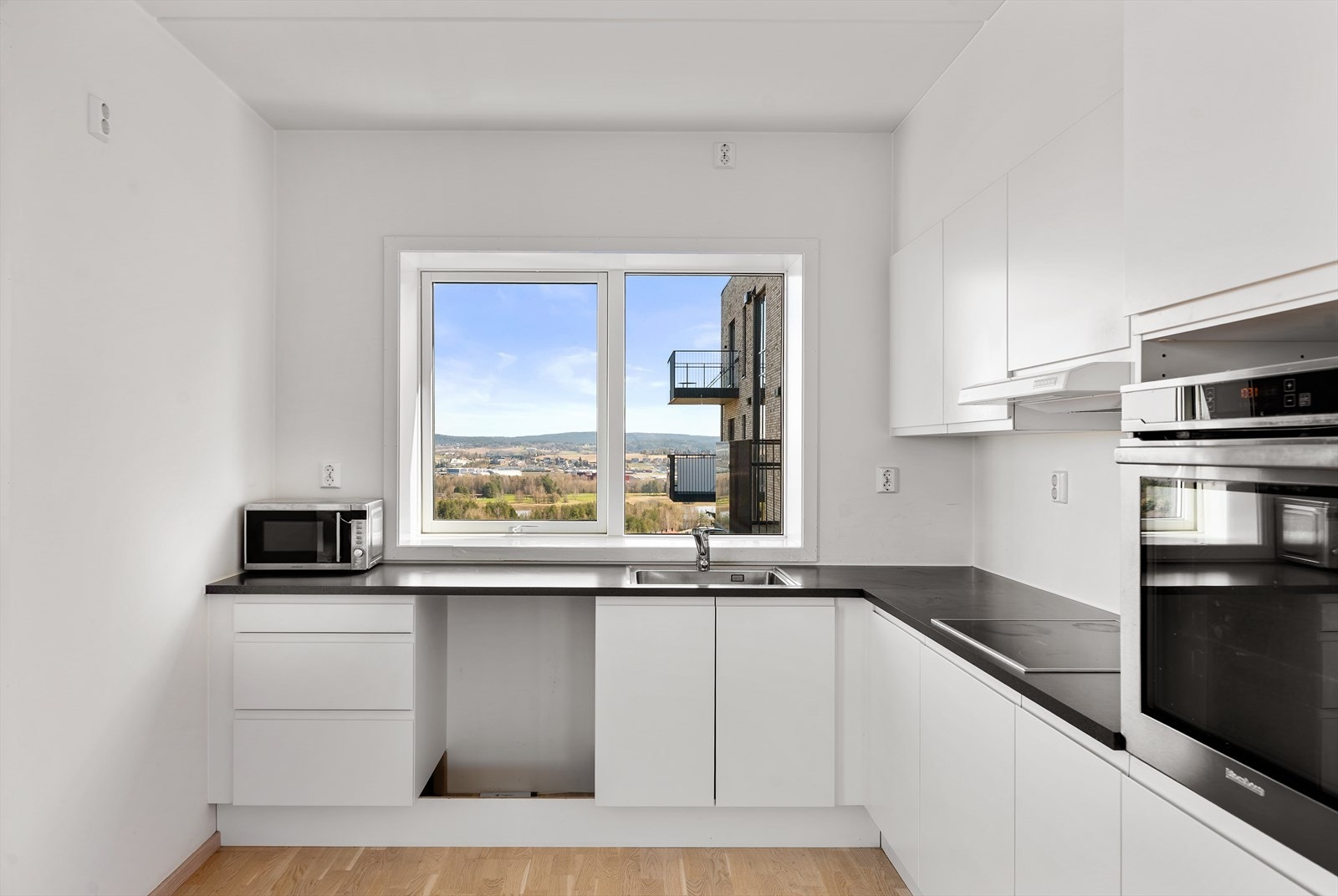 Kjøkkeninnredning med glatte fronter og laminatbenkeplate. Avtrekket er koblet til det balanserte ventilasjonsanlegget. Galleribilde