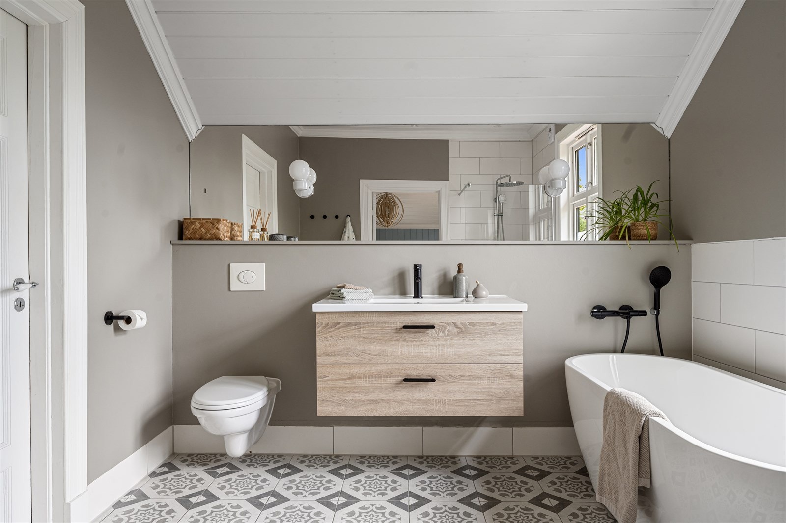 Badet i 2. etasje er lekkert innredet og tilknyttet hovedsoverommet. Rommet har flislagt gulv og vegger med stilrene detaljer, nedsenket himling med downlights, og behagelige varmekabler i gulvet. Galleribilde