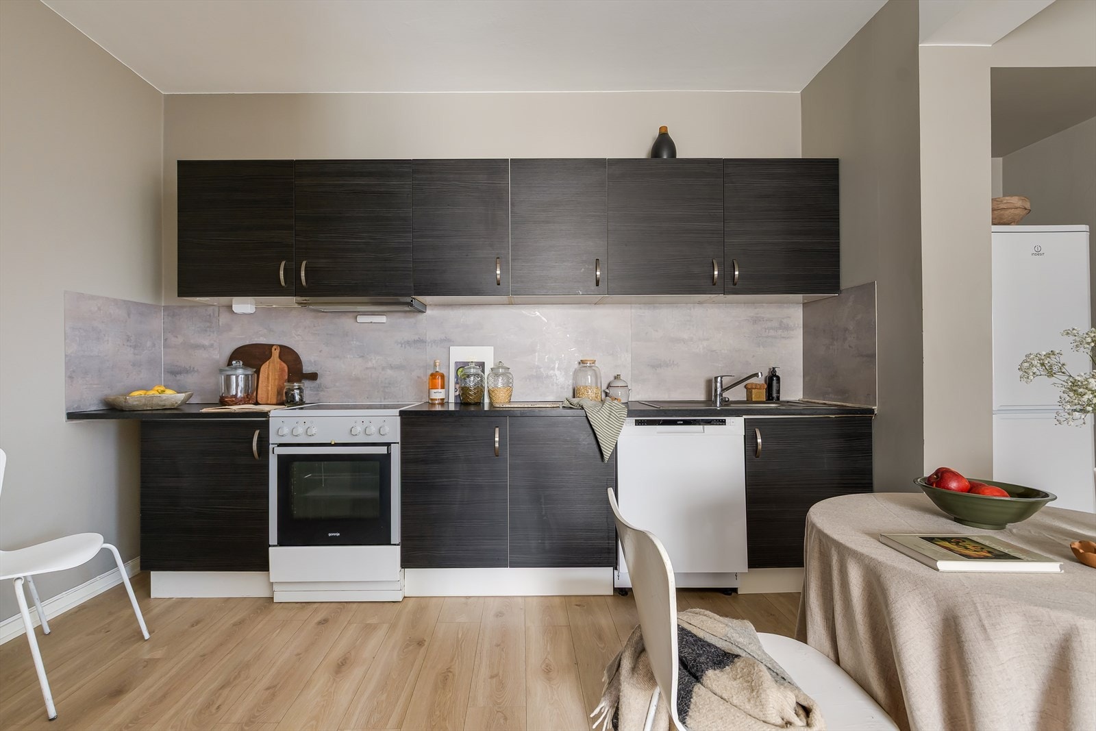 Flott kjøkkeninnredning med mørke, glatte fronter og benkeplate i laminat. Den funksjonelle og praktiske utformingen gir godt med skap- og benkeplass. Galleribilde