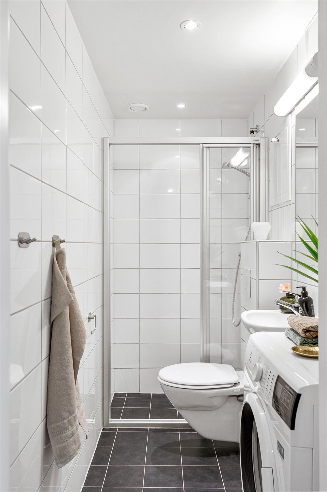 Badet er innredet med veggmontert WC, dusjplass med dusjvegger og servant med ettgreps blandebatteri. Galleribilde