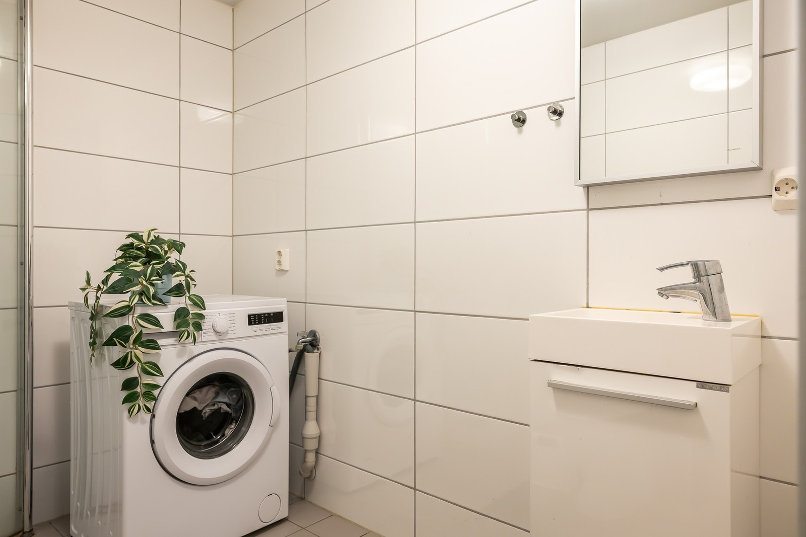 Innredningen består av en heldekkende servant på hvitt skap, speil og det er opplegg for vaskemaskin. Galleribilde