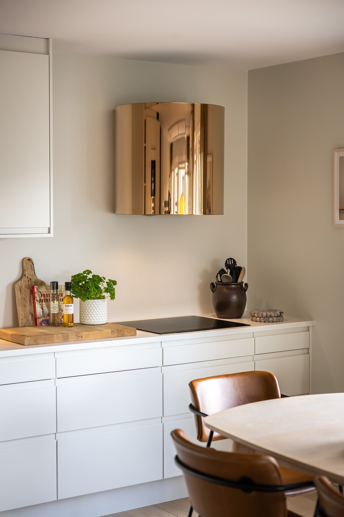 I hjørnet er kjøkkenet utstyrt med en integrert induksjonstopp og over kokesonen er det en moderne ventilator i messingfarge med avtrekk ut. Det er montert både waterguard og komfyrvakt. Galleribilde
