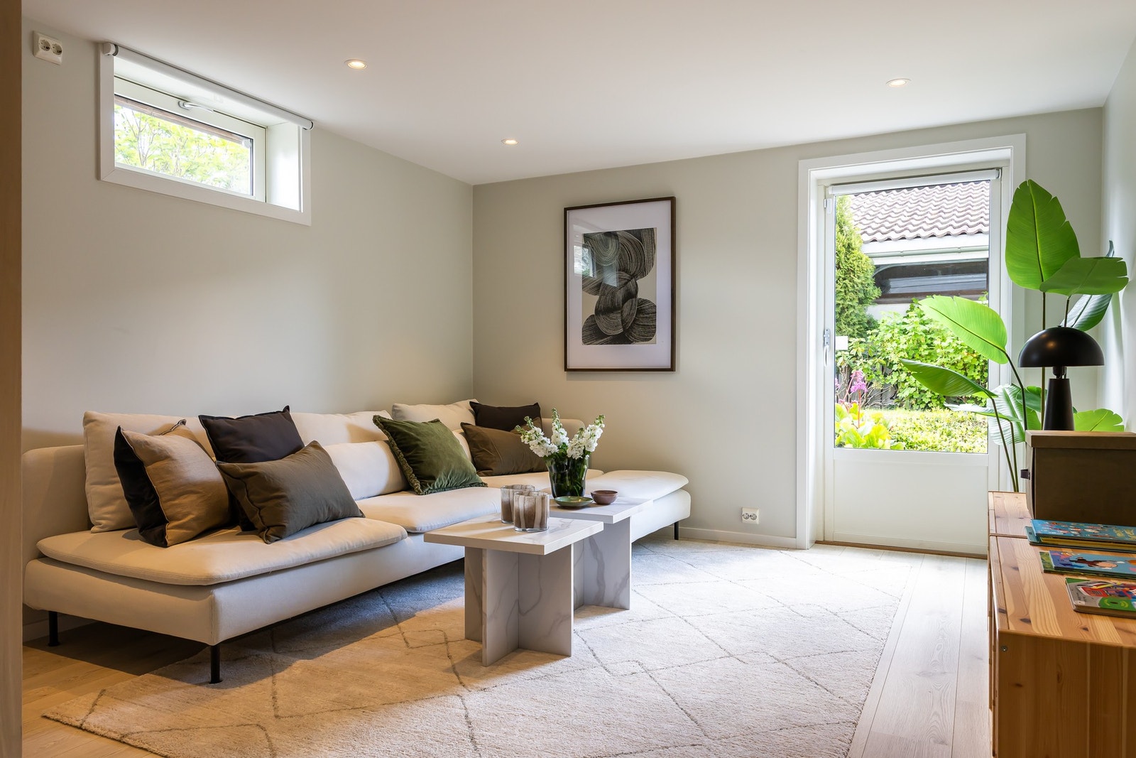 Kjellerstue/tv-stue med varmefolie i gulvet. Stuen har lysmalte vegger, listefri himling med downlights og terrassedør ut mot hagen. Galleribilde
