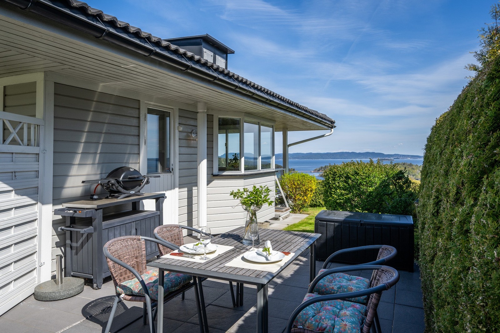 Lun, usjenert og hellelagt terrasse avskjermet med hekk Galleribilde