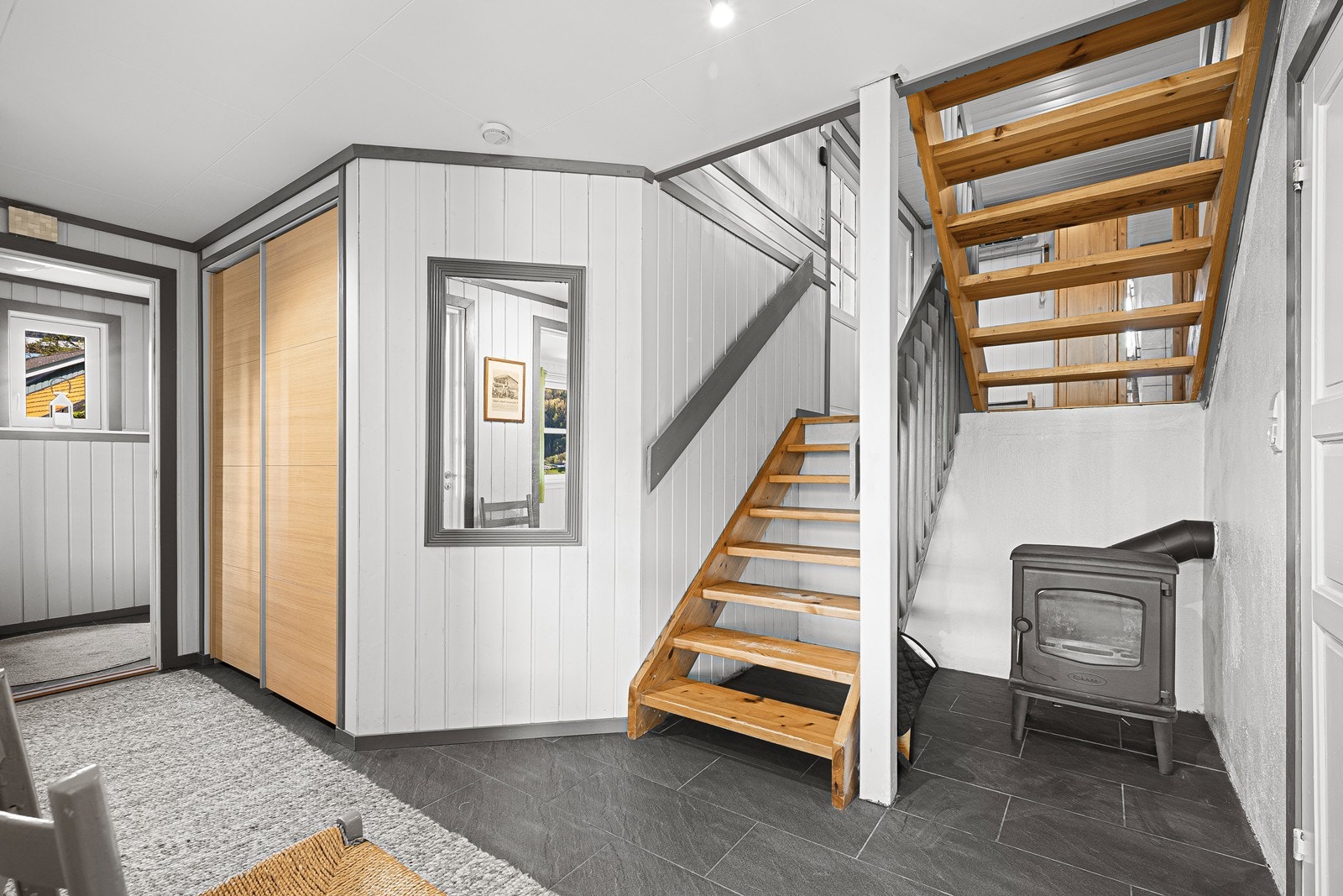 Velkommen inn! Entré med skyvedørsgarderobe til yttertøy og vedovn for oppvarming Galleribilde