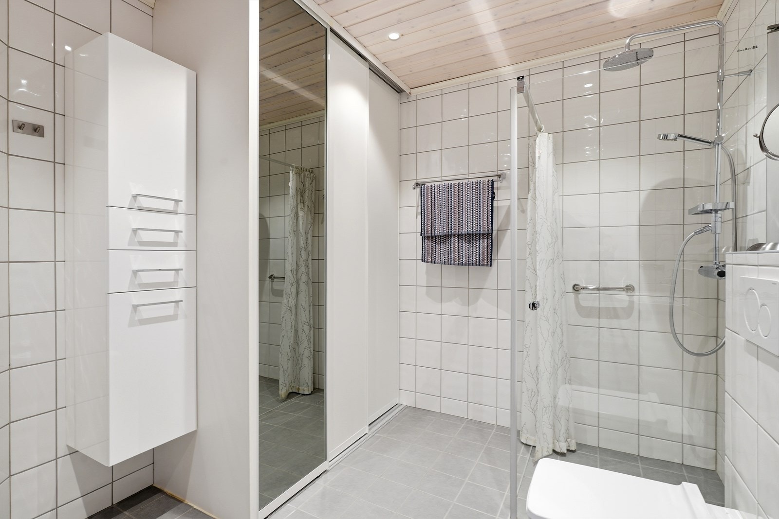 Skyvedørsgarderobe og vegghengt innredning gir praktisk oppbevaring på badet. Galleribilde