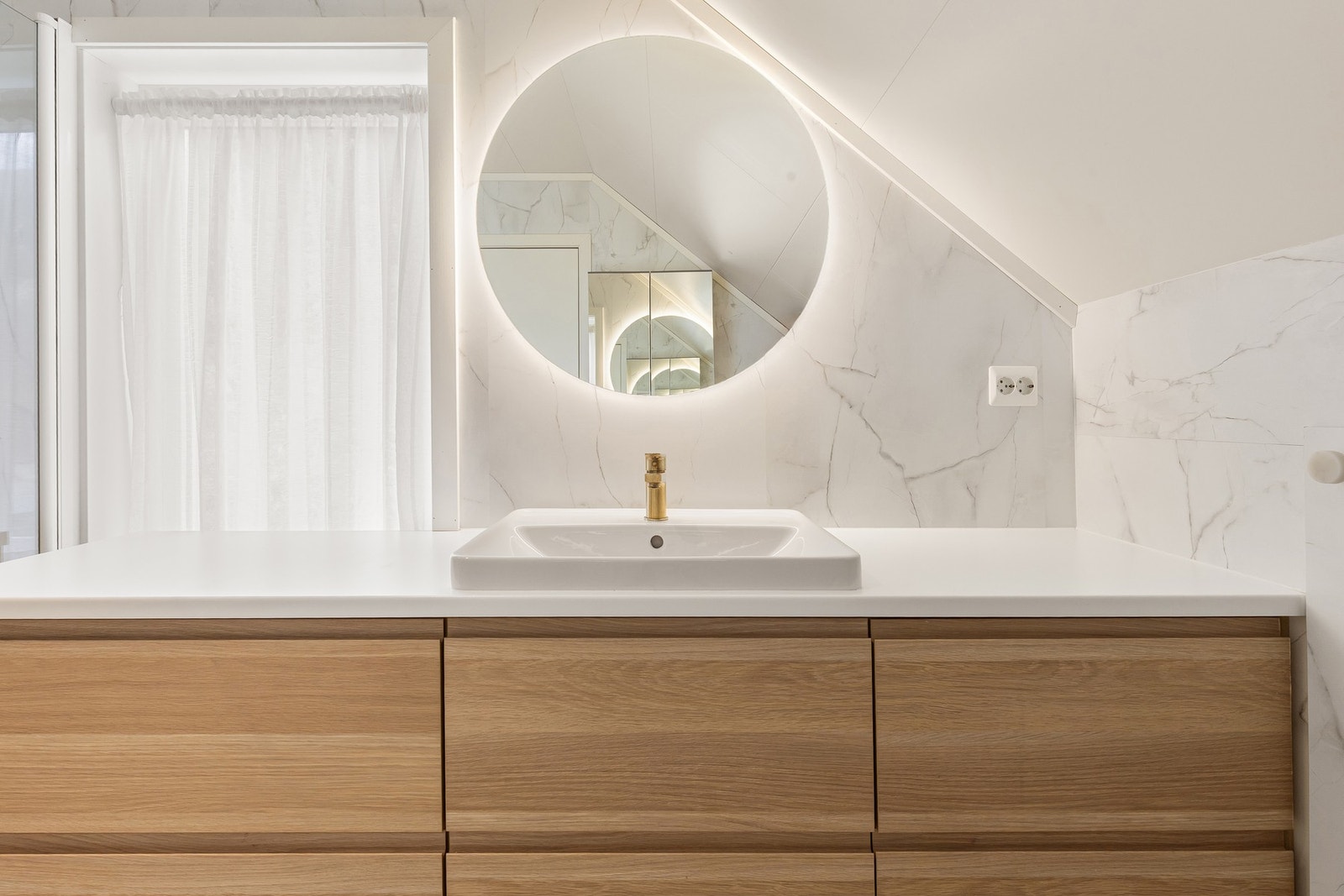 Innredning med heldekkende servant og et elegant, bakbelyst speil. Galleribilde
