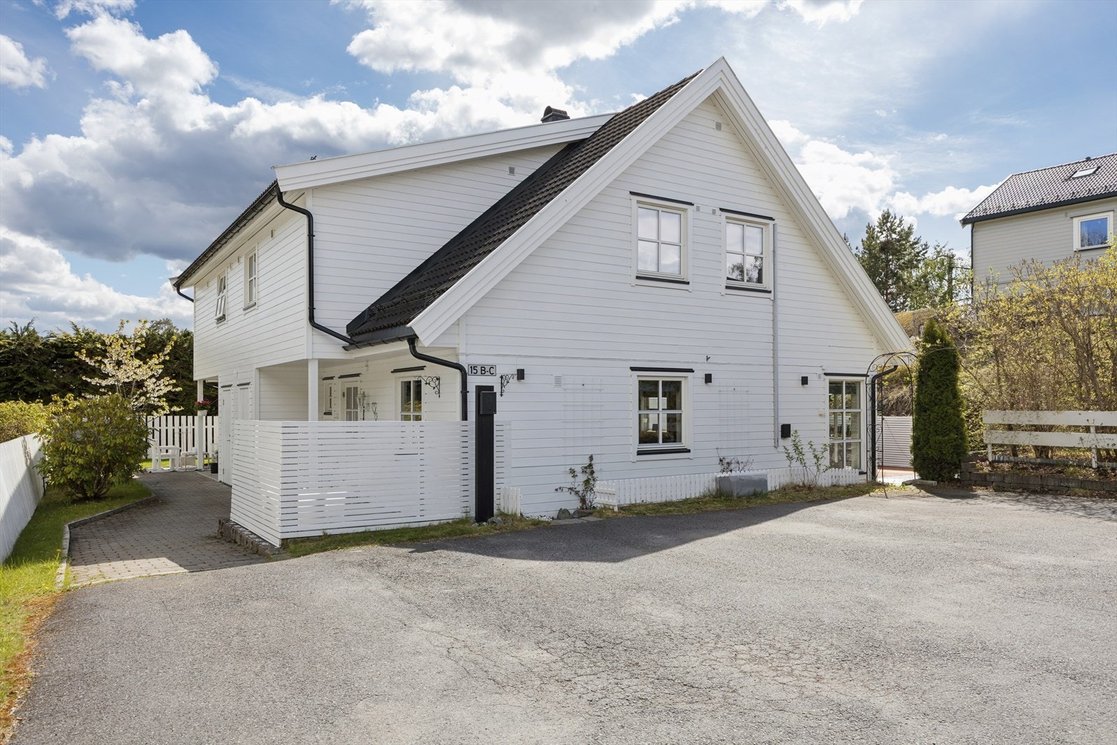 Asfaltert gårdsplass med to parkeringsplasser og lader montert. Galleribilde