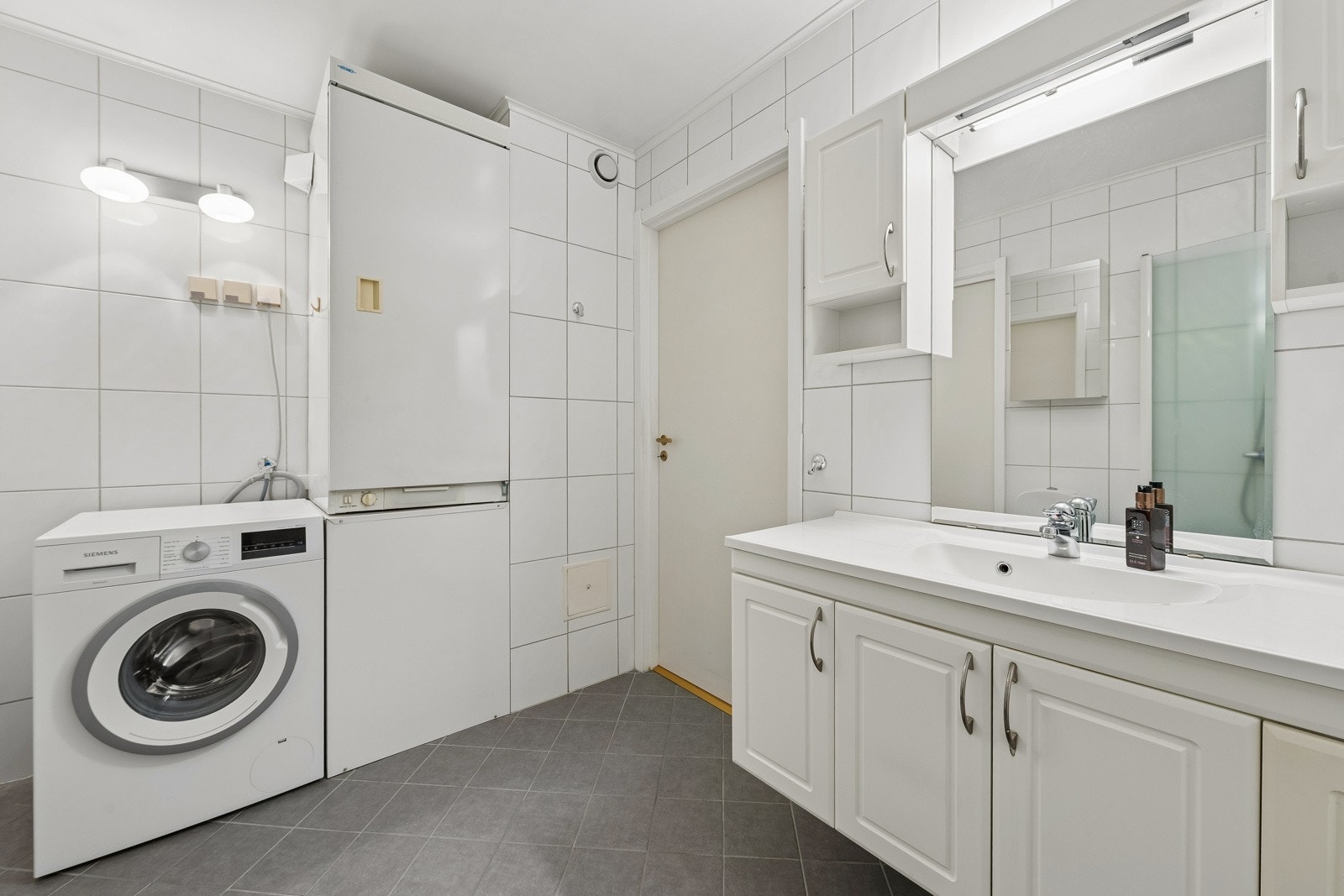 Badet består av toalett, servant og dusj i hjørne med innad slående dører. Det er også opplegg for vaskemaskin og tørketrommel, samt et praktisk tørkeskap. Galleribilde