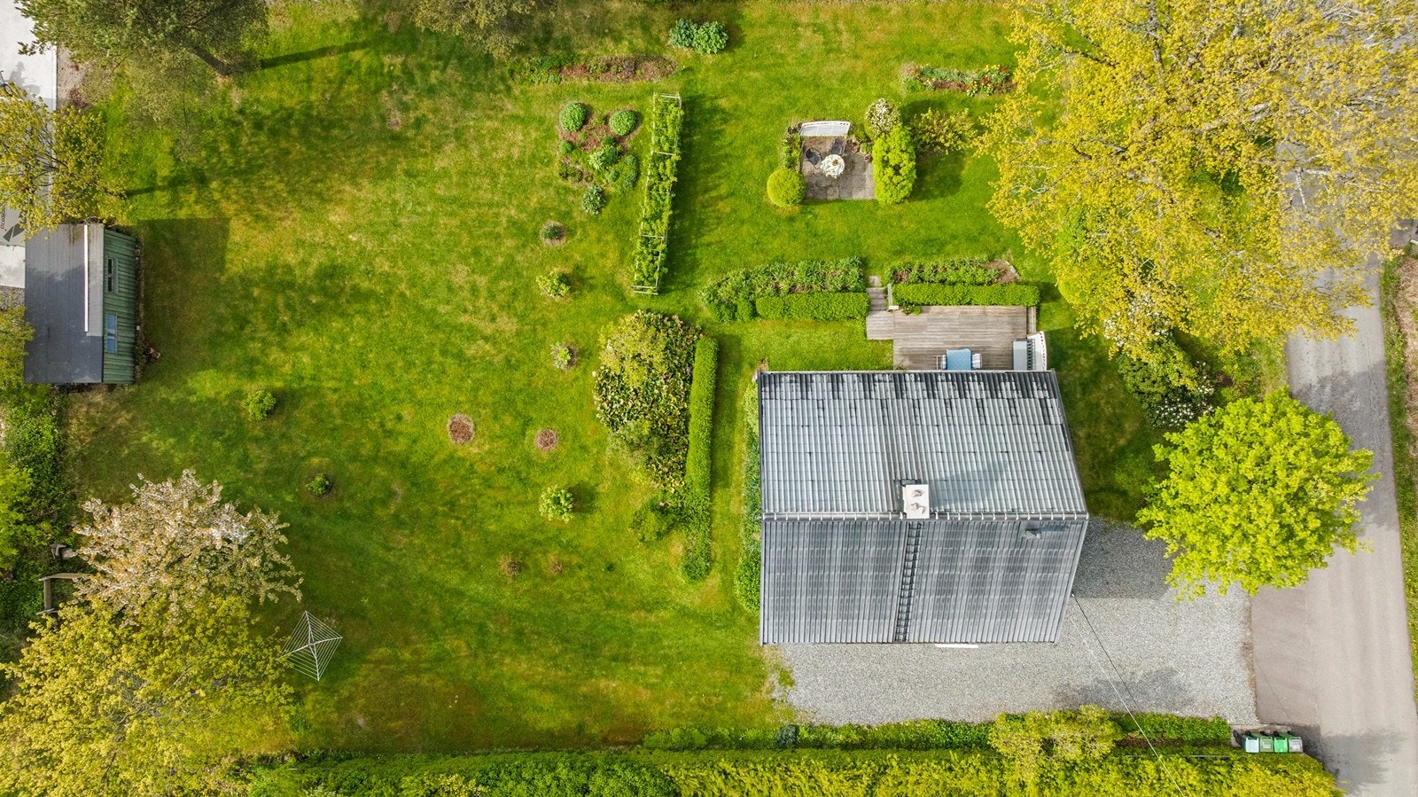 Tomten er opparbeidet med plen, hekker og diverse beplantning, samt en frittstående bod. Galleribilde
