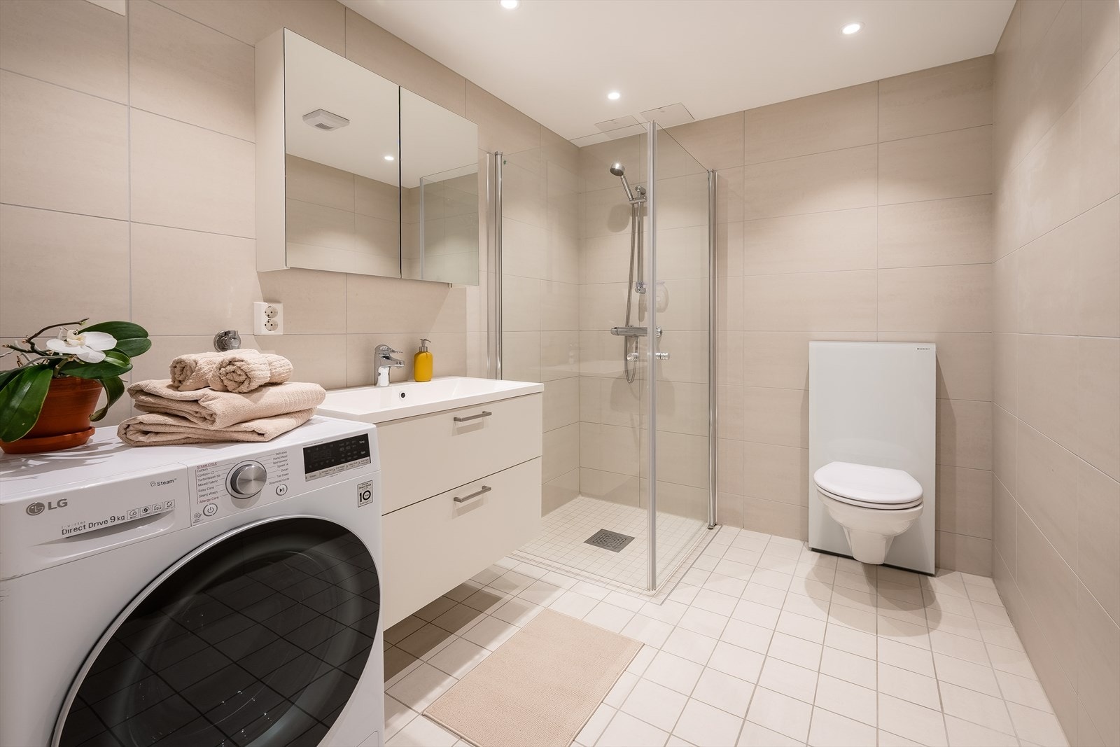 Romslig og flislagt bad med gulvvarme, downlights og opplegg for vaskemaskin. Galleribilde