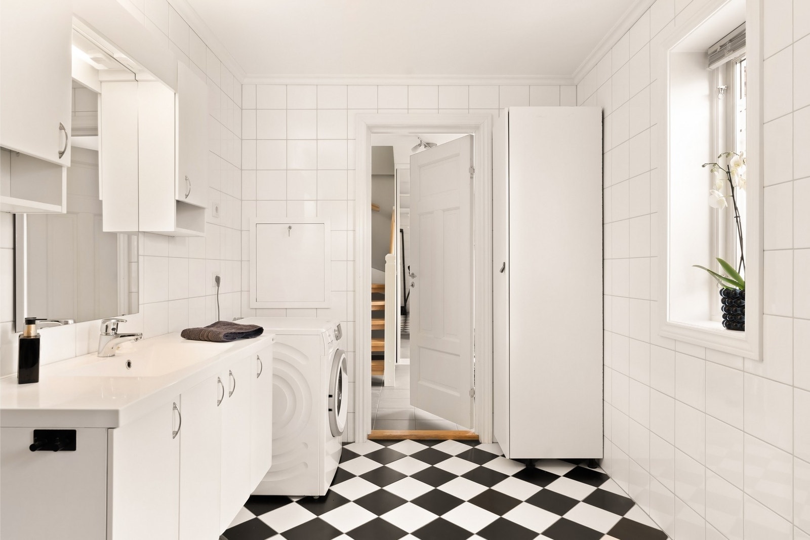 Badet har en god størrelse og er innredet med gulvstående wc, opplegg for vaskemaskin, stor baderomsinnredning og dusjkabinett Galleribilde