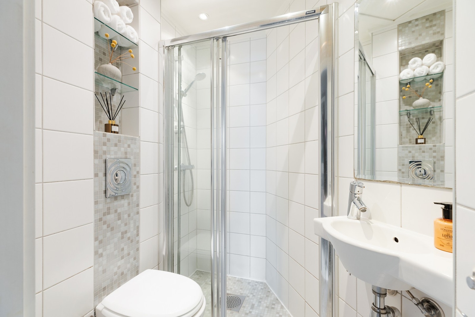 Tidløst baderom med gulvvarme. Badet er innredet med vegghengt toalett, servant og dusjhjørne med glassdører. Galleribilde