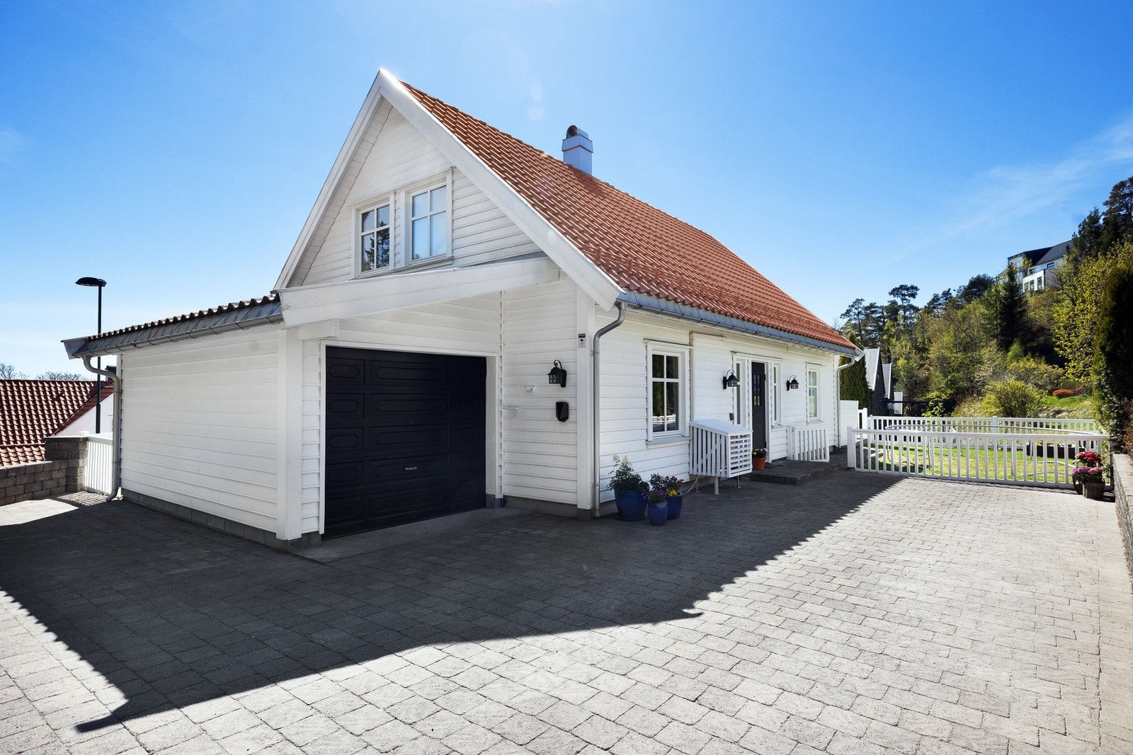 Eneboligen har en romslig steinbelagt gårdsplass og garasje med elbil-lader. Galleribilde