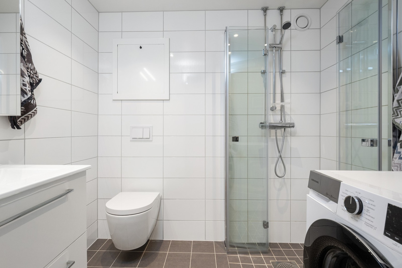 Badet ble totaloppusset i regi av borettslaget i 2024. Gulvet har grå fliser med varme, mens veggene er kledd med hvite fliser. Det er opplegg for vaskemaskin. B Galleribilde