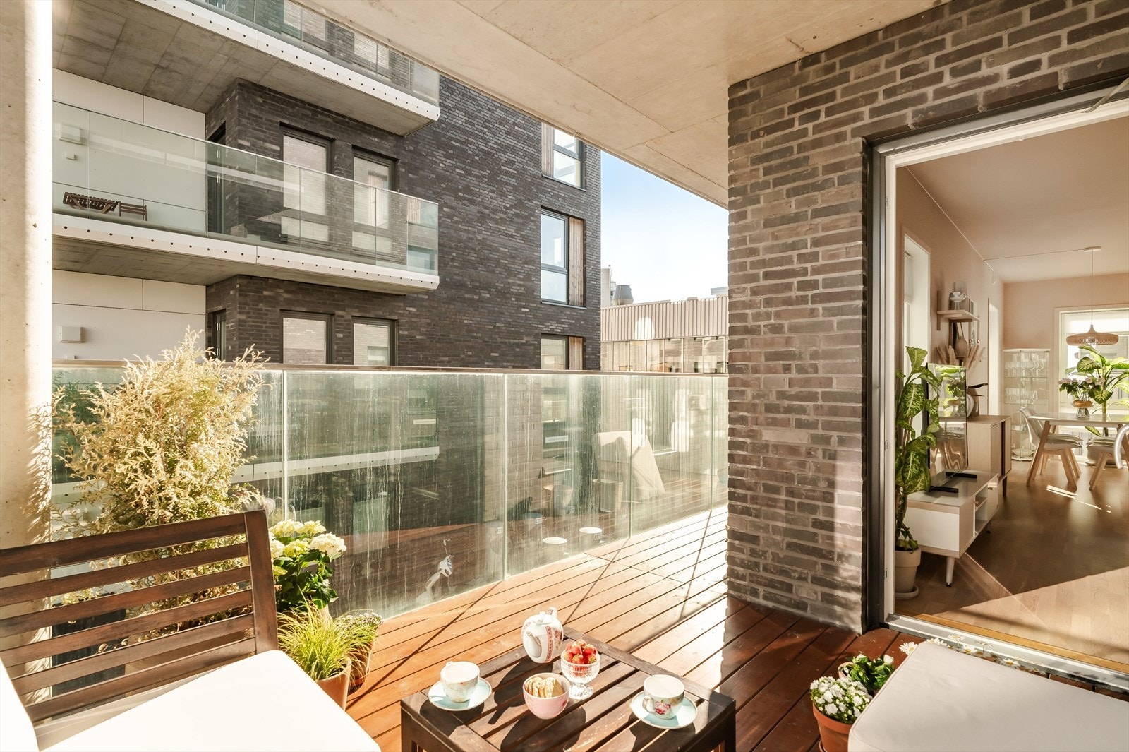 Balkongen har terrassebord på gulv, glassrekkverk og god plass til utemøbler og beplantning. Galleribilde