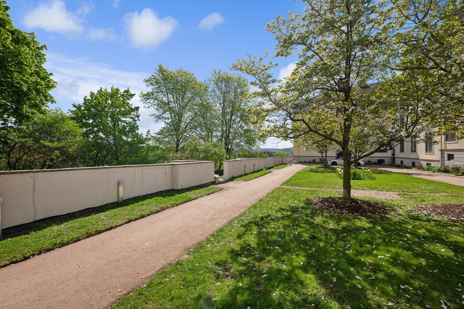 Gårdsrommet er opparbeidet med store gressplener, blomster og prydbusker, Syrin- og Magnoliatrær og idylliske internveier med rød sandstrøssel. Galleribilde