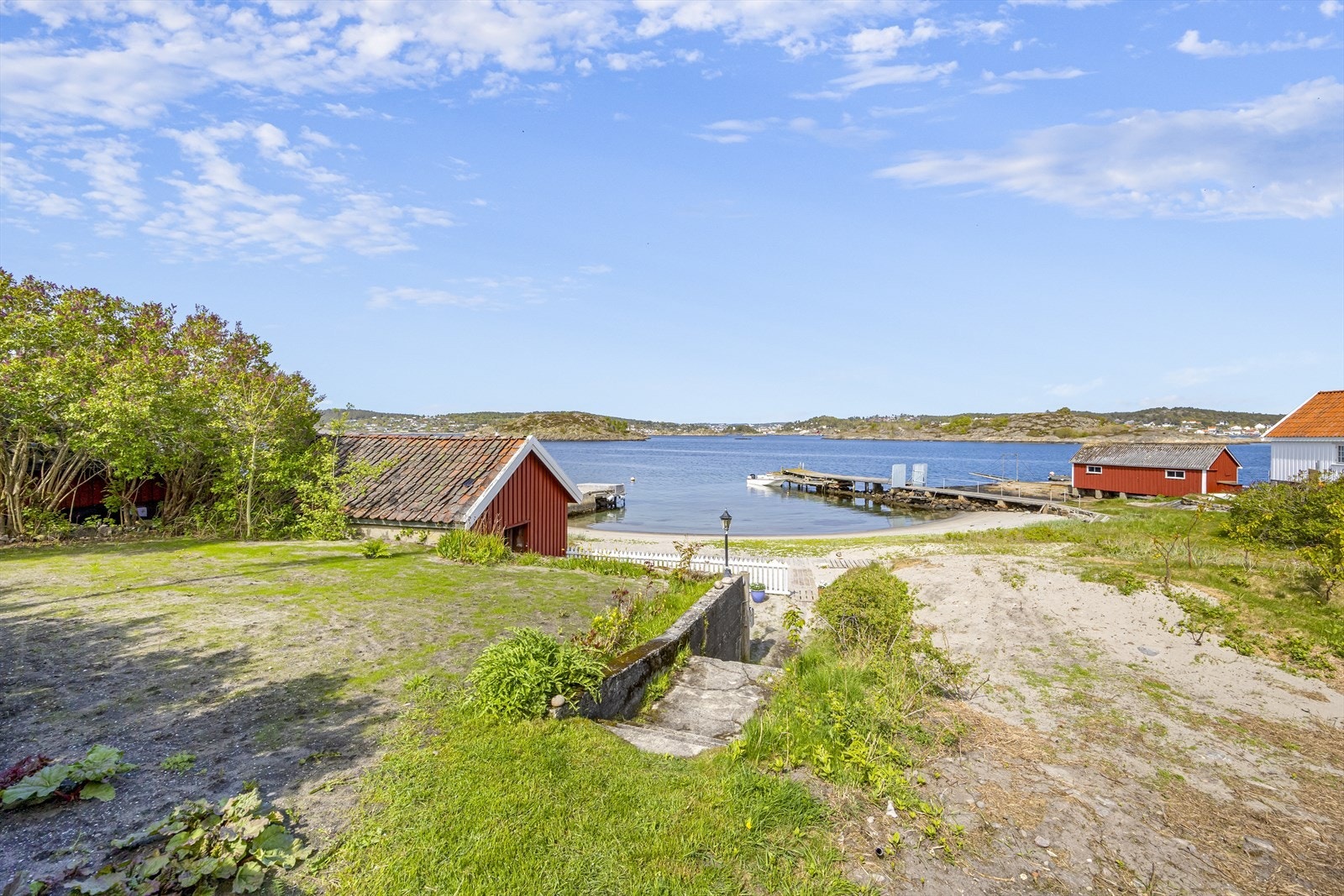 Tomten er opparbeidet med hage på flere nivåer fra strand og sjøbod med tilhørende platting samt usjenert hage over 2 nivåer hvor det er grovplanert med murer, hekk og noe beplantning. Galleribilde