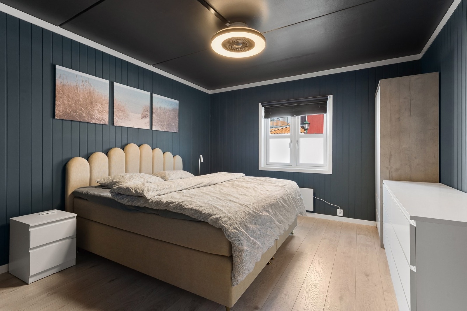 Soverommet har mørke vegger, lyst gulv, vindu og en moderne taklampe. Galleribilde