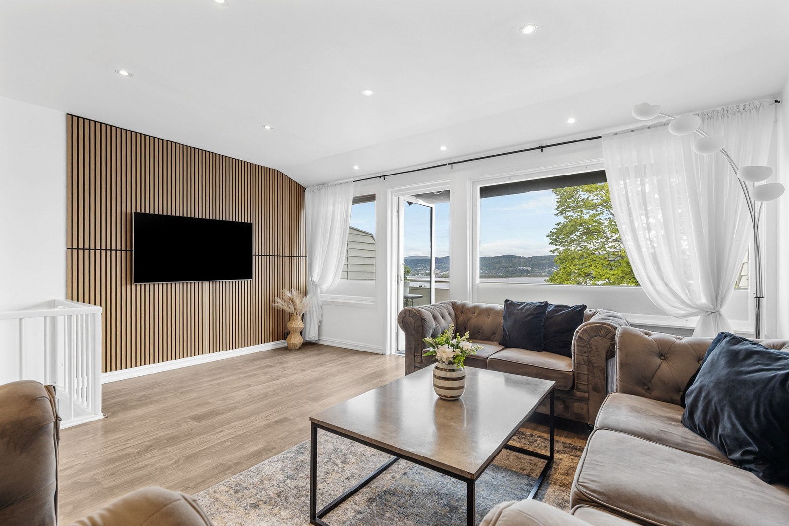 Innbydende stue med 1-stavs laminatgulv, hvitmalte vegger kombinert med spilevegg og downlights i himling Galleribilde