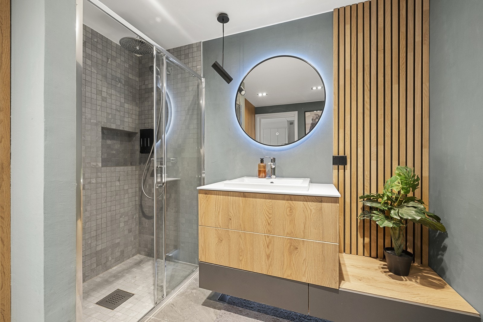 Badet er moderne og funksjonelt innredet med vegghengt toalett og servantinnredning med servant og ettgreps blandebatteri. Dusjdør i glass og armatur i moderne utførelse. Galleribilde