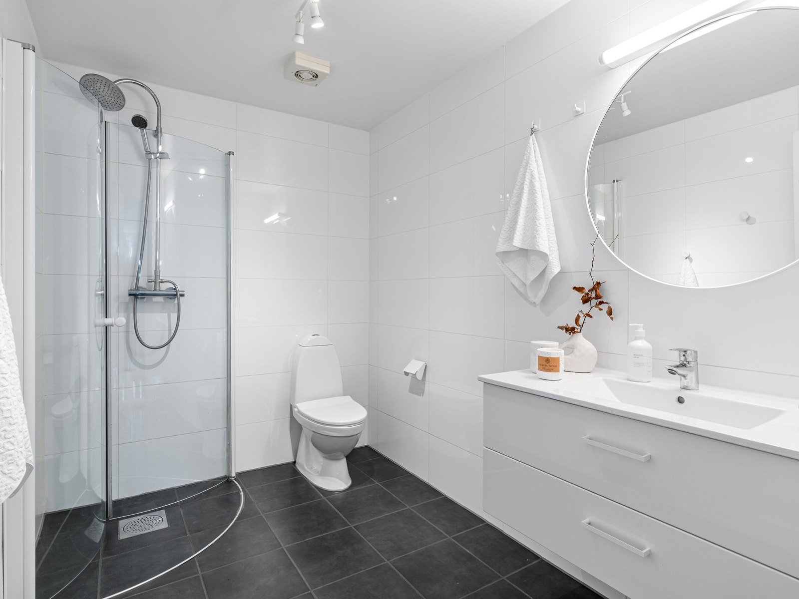 Badet i underetasjen er fra ca. 2010 og har fliser på gulv og vegger, samt gulvvarme. Badet er utstyrt med servantskap og speil. Videre er rommet utstyrt med toalett og dusj. Galleribilde