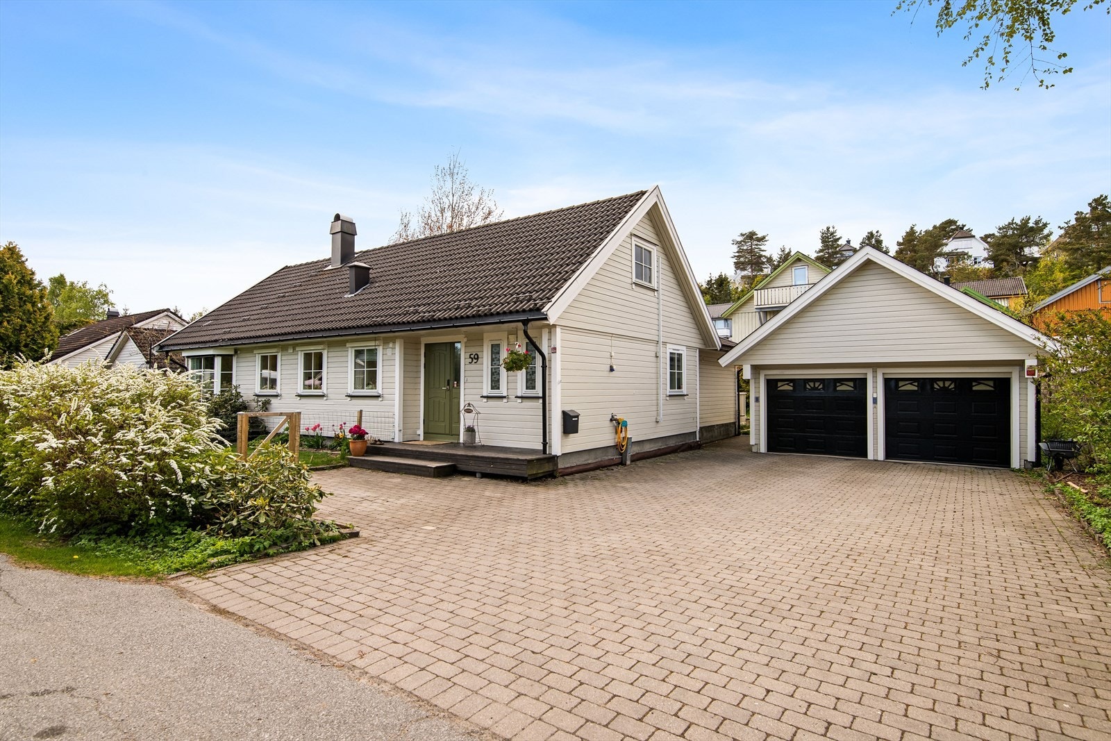 Gårdsplassen er belagt med flott belegningsstein som leder frem til en romslig, frittstående dobbeltgarasje, noe som gir et meget godt førsteinntrykk og rikelig med parkeringsplass. Galleribilde