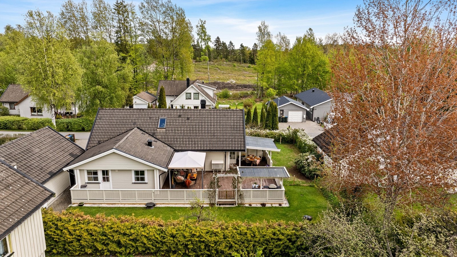 Hagen er en grønn oase med flat plen som innbyr til lek, prydbusker og en lun, hvitblomstrende hekk som skjermer godt. Galleribilde