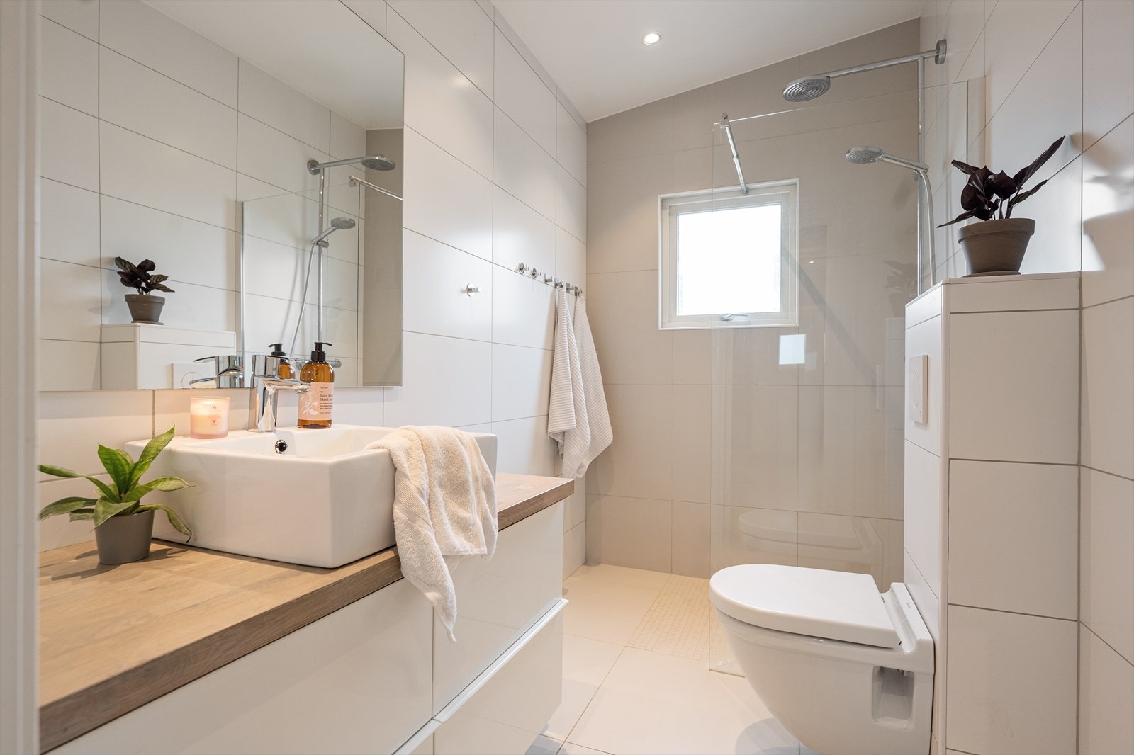 Pent bad med flislagte overflater, downlights i himling og varmekabler i gulv. Galleribilde