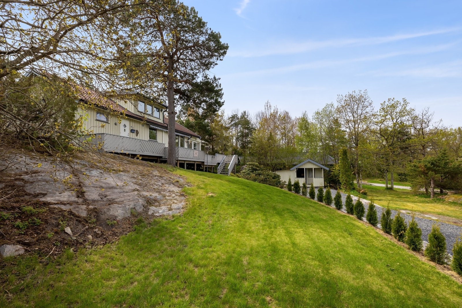 Tomten er pent opparbeidet med gressplen og delvis naturtomt Galleribilde
