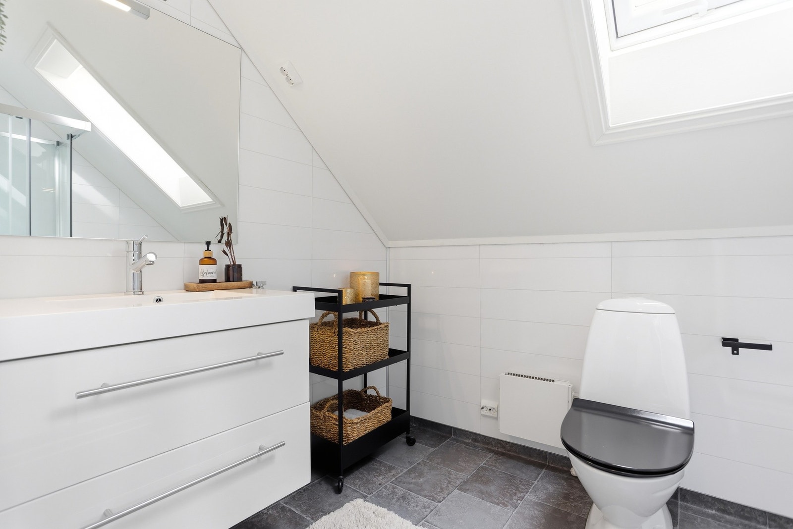Pent og moderne bad med opplegg til vaskemaskin. Rommet er utstyrt med toalett, dusjkabinett, innredning med skuffer og heldekkende servant. Galleribilde